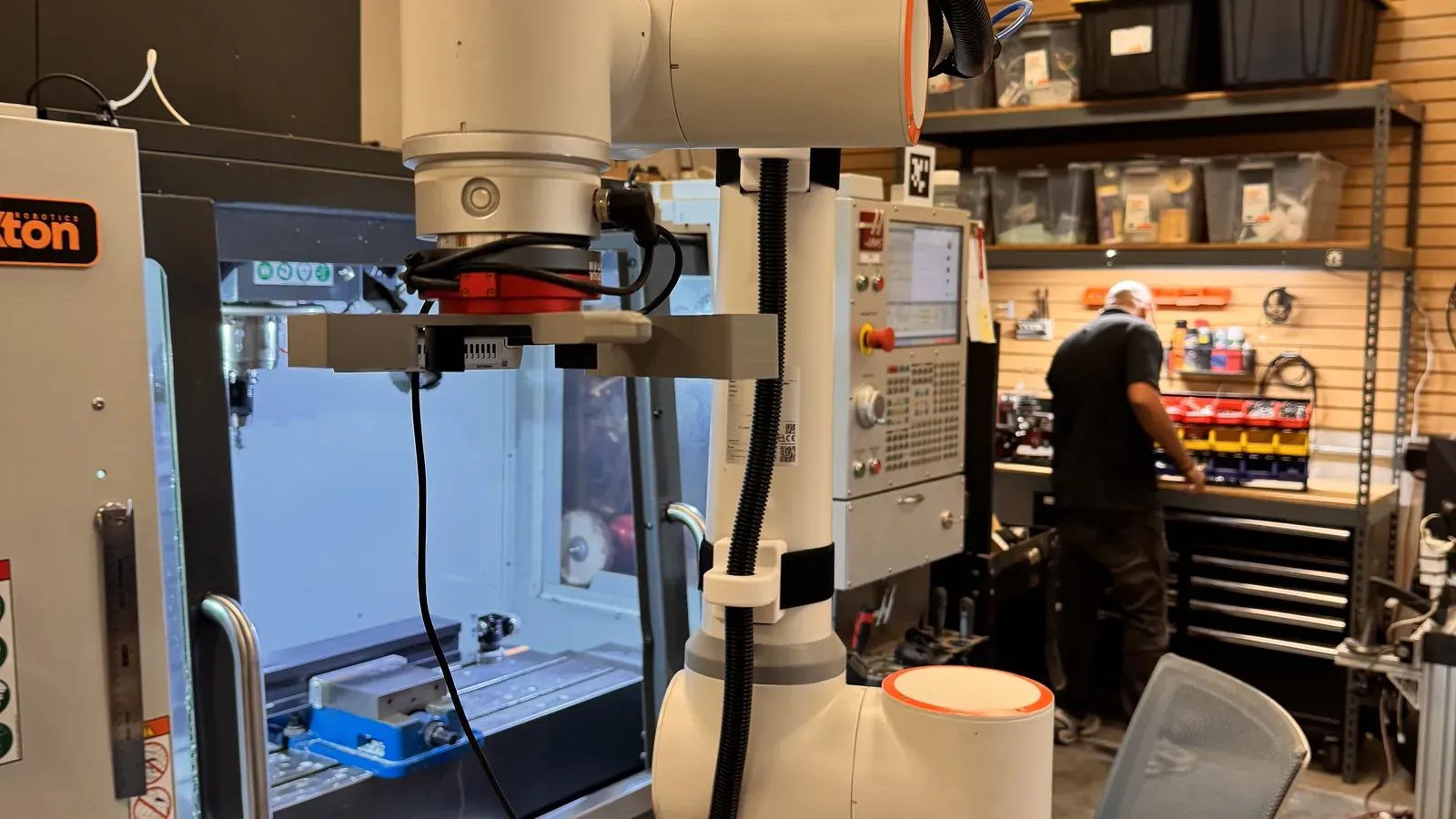 Cobot with gripper next to a Haas CNC mill with an AprilTag marker on the control in the Axton Robotics test cell