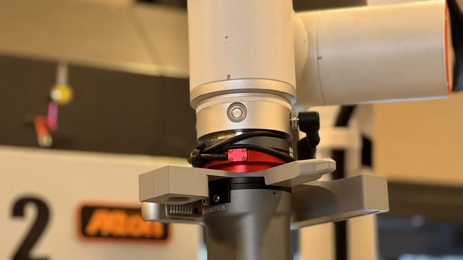 Close-up of a cobot wrist with its vision camera mounted under the gripper bracket, beside a Haas CNC mill